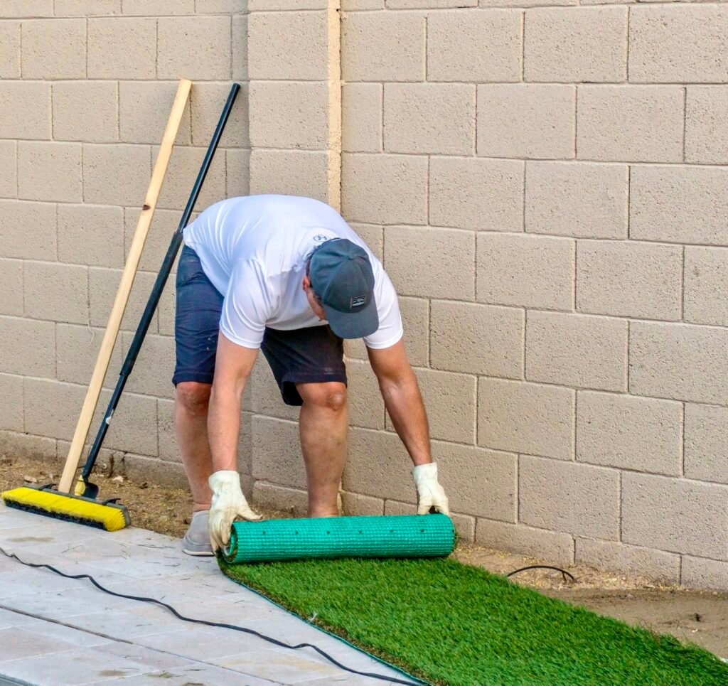 Adult male rolling out a piece of artificial turf or grass