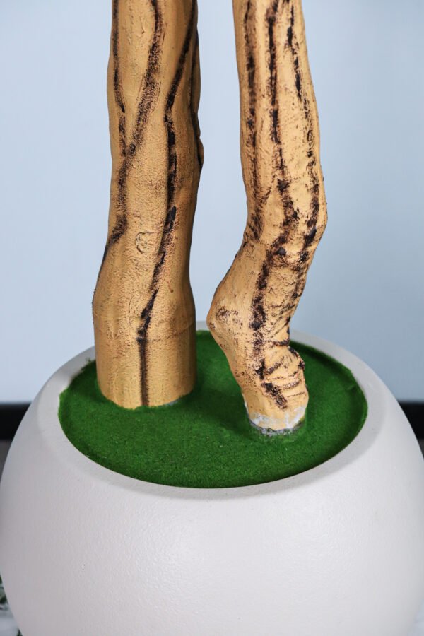 The base of the faux tree, showing the lifelike moss within a minimalist white pot.