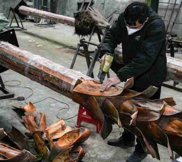 Workers treating palm leaves in factory