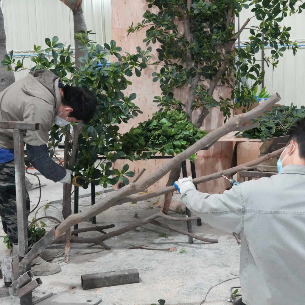 Oakco workers assembling large artificial tree branches by hand in factory workshop