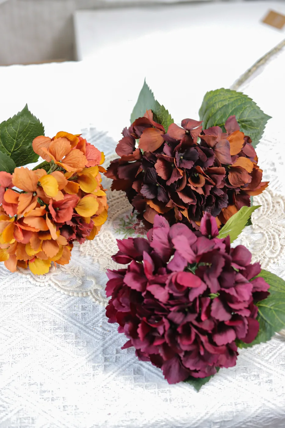 Artificial hydrangea heads showing orange burgundy and purple colour options