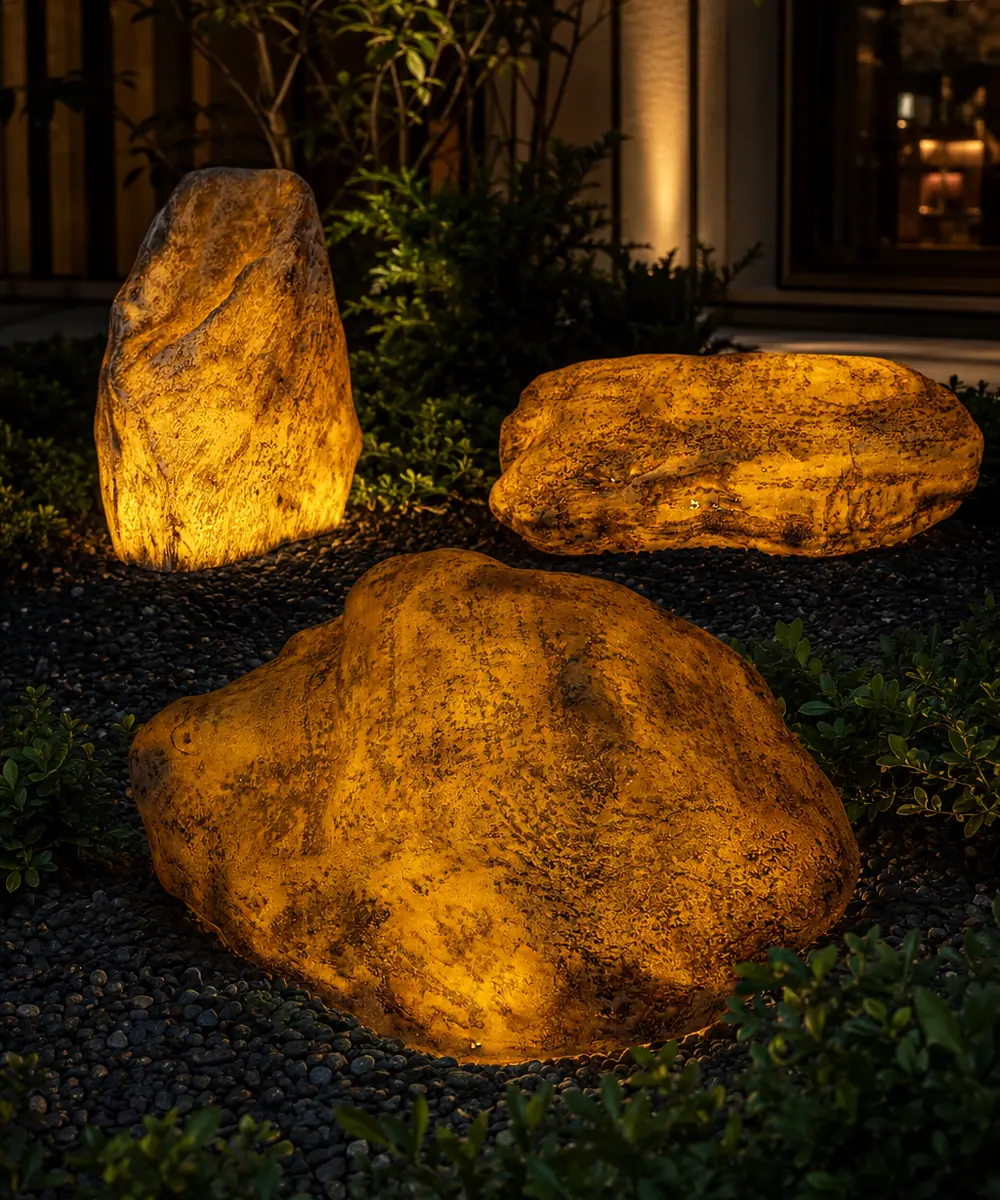 Warm illuminated artificial rocks revealing textured surfaces in a hospitality landscape after dark