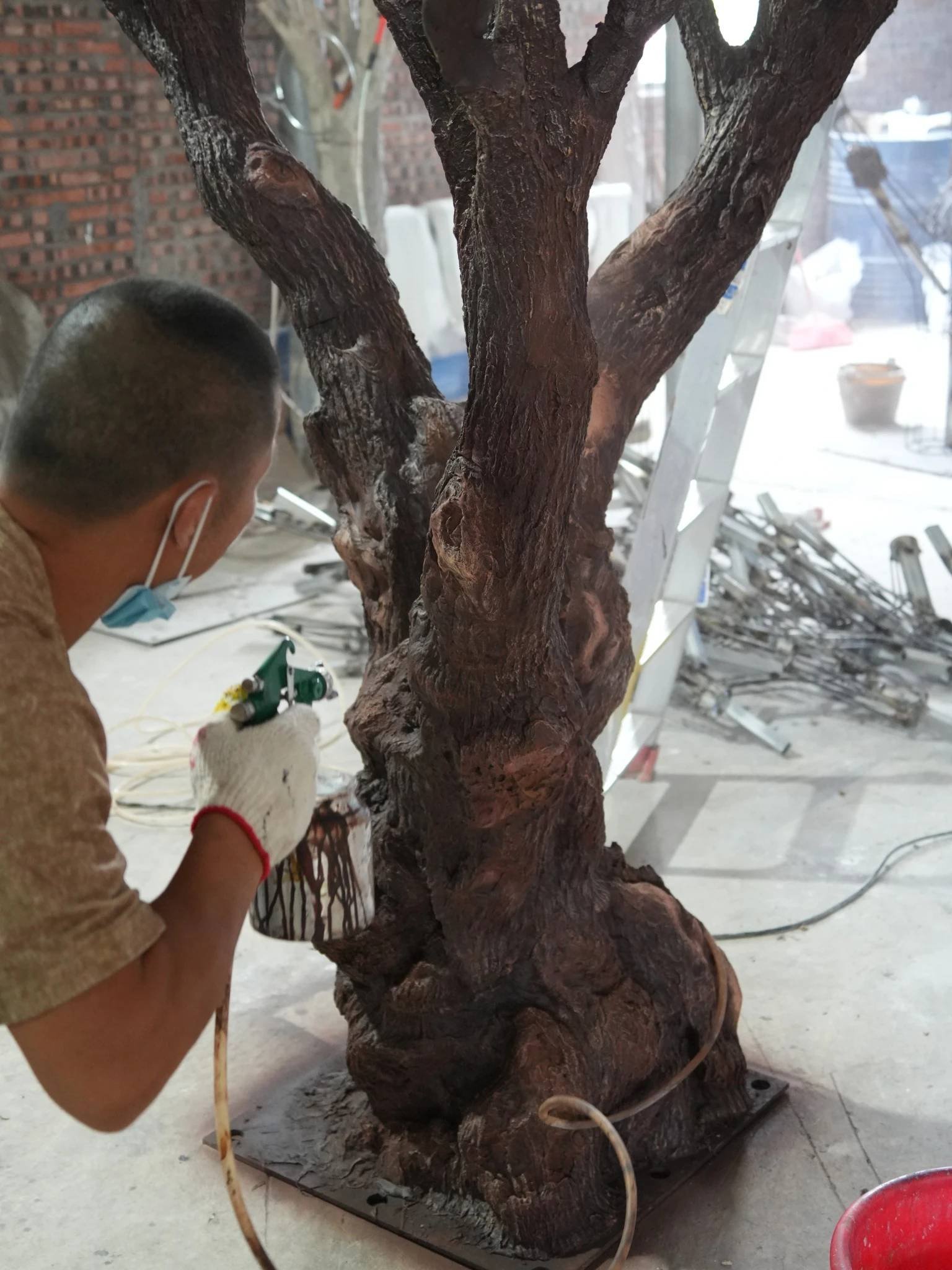 Oakco artisan spray-colouring an artificial tree trunk during the finishing process