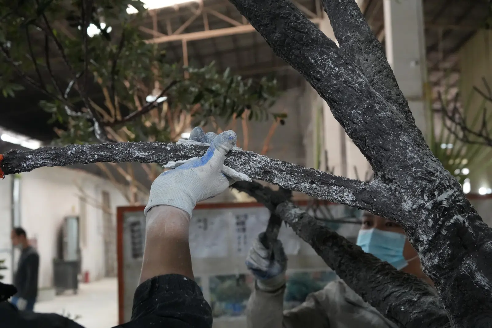 Oakco artisan applying realistic bark texture by hand to an artificial tree branch