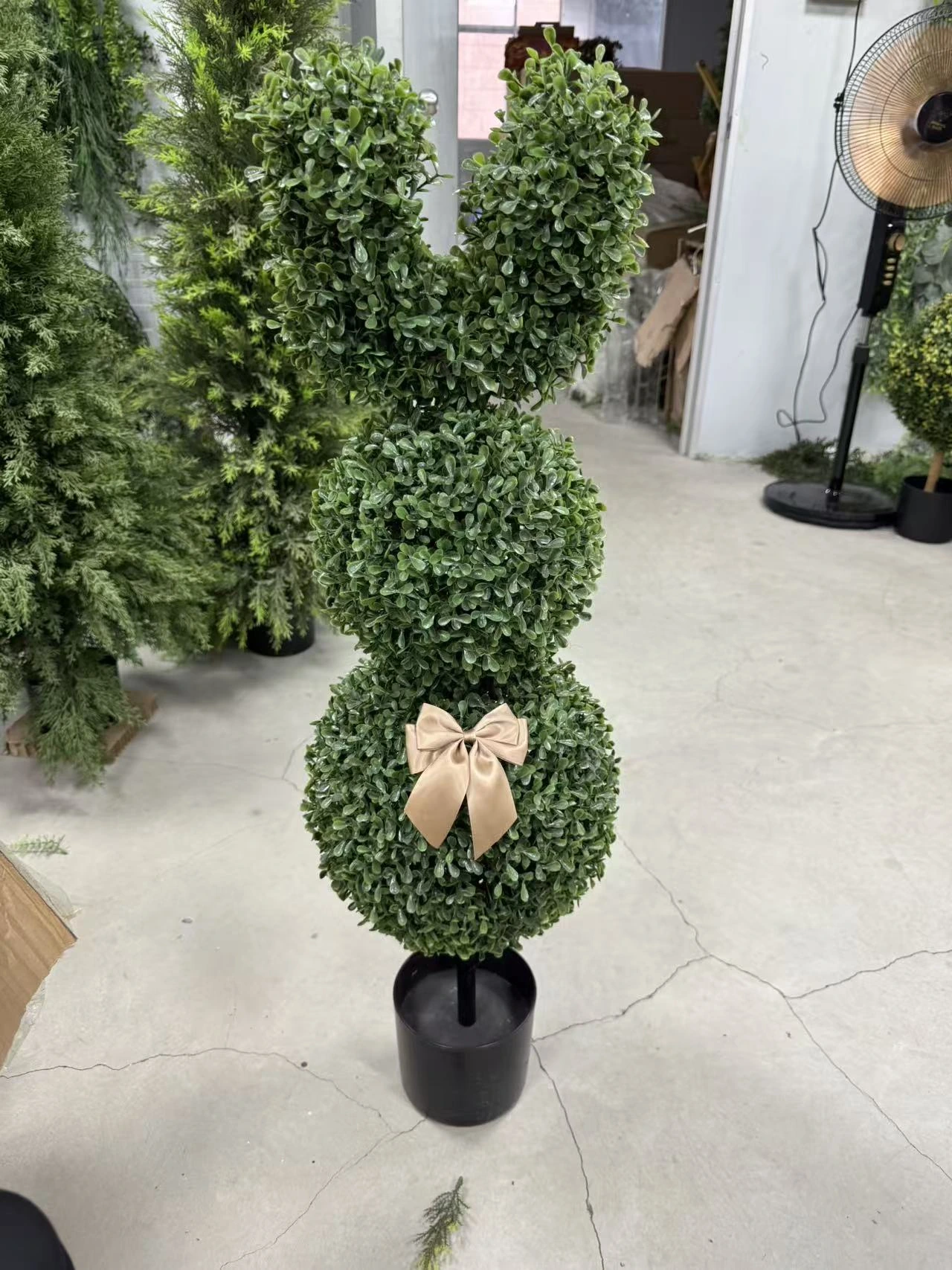 Rabbit-shaped artificial topiary with a beige bow in a black plastic pot