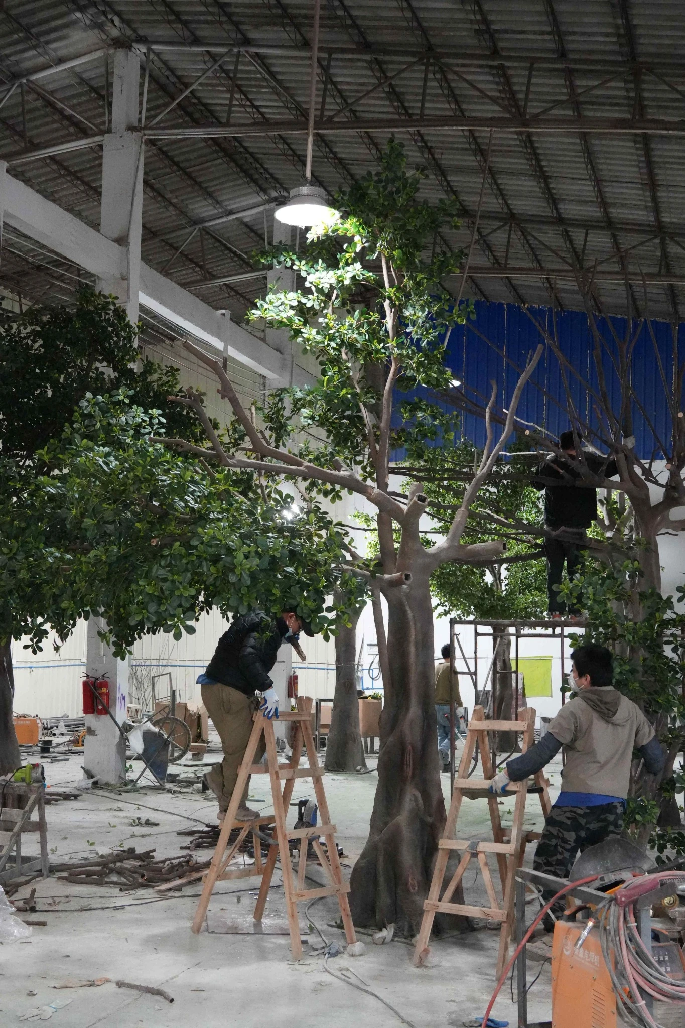 Large artificial banyan tree undergoing workshop pre-assembly and structural checking before packing