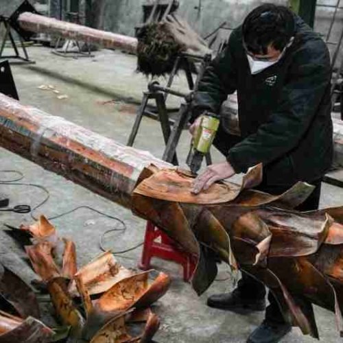 An Oakco craftsman performing the precise hand-binding of natural palm bark onto a reinforced internal structure, ensuring a seamless and authentic trunk finish for bespoke artificial trees.